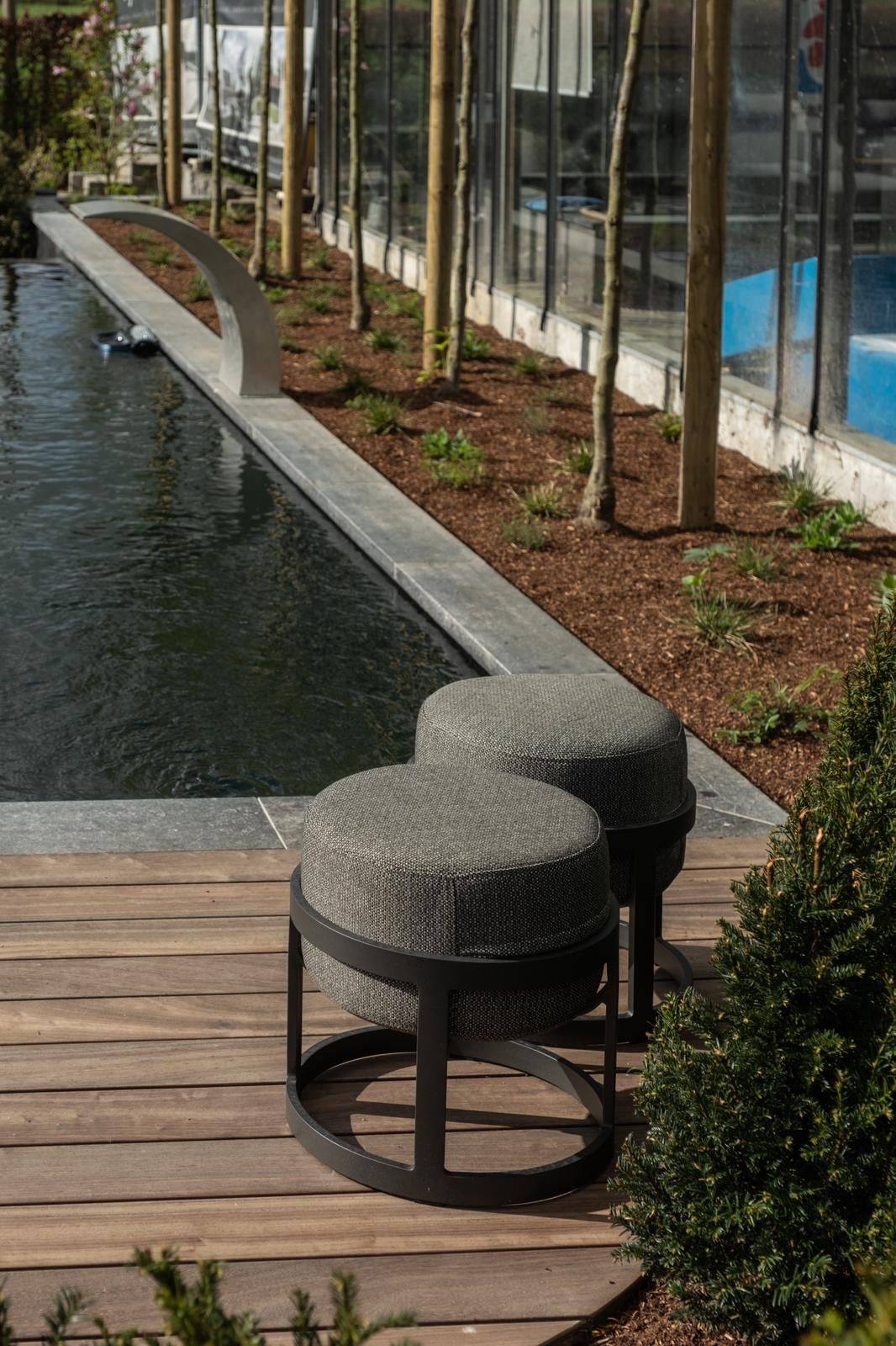 Hardhouten terras met grijze poefjes langs een lange ecologische vijver