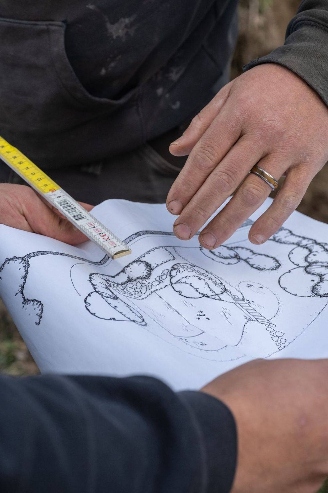 Vakman bestudeert het tuinontwerp met een meter in de hand